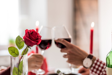 Young happy couple celebrating Valentine's day with a dinner at home drinking wine, cheers.