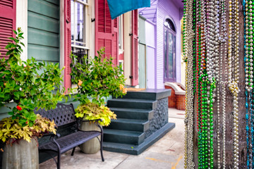 Fototapeta na wymiar Mardi Gras beads decorate a telephone pole on a New Orleans street of colorful houses