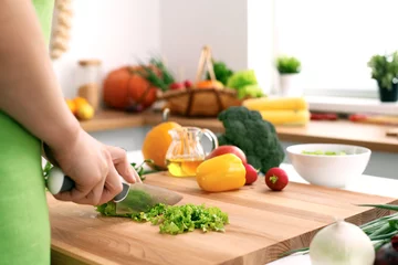 Close up of  woman's hands cooking in the kitchen. Housewife slicing ​​fresh salad. Vegetarian and healthily cooking concept