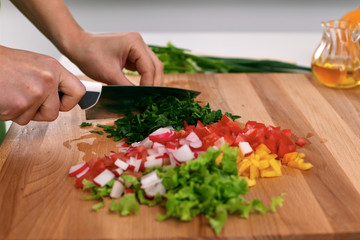 Close up of  woman's hands cooking in the kitchen. Housewife slicing ​​fresh salad. Vegetarian and healthily cooking concept