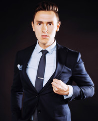 young pretty business man standing on black background, modern h