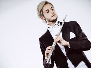 Male flutist wearing tailcoat holds flute
