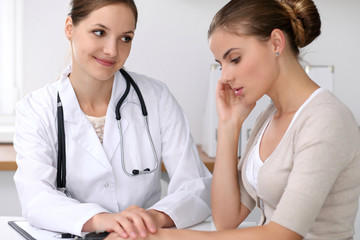 Doctor reassuring her female patient while  sitting at the desk. Medicine, help and health care concept