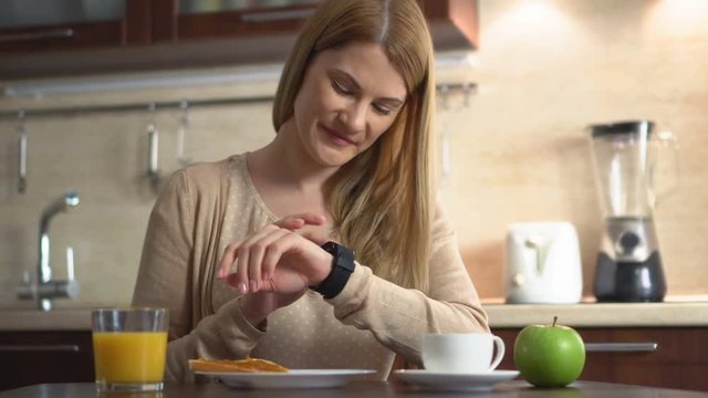Beautiful young woman making various gestures with her finger on a touch screen of her smart watch.