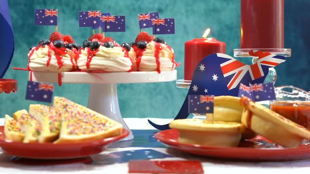 Australian theme party table with flags and iconic food including mini pavlovas, lamingtons, meat pies and fairy bread, close up static.