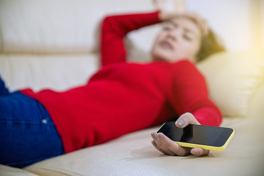 Woman serious then sleep and holding a mobile phone in the sofa inside home