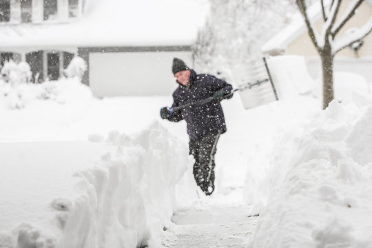 Man shoveling snow (shallow depth of field, focus on snow in for