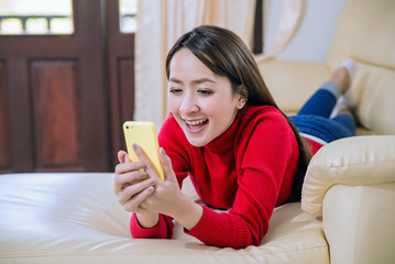 Pretty young woman happy smile using mobile phone on couch in home relax day