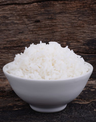 Cooked rice in bowl on wood background.