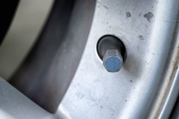 selective focus on stem on car wheel - Car wheel on a car, closeup on alloy metal circle disk wheel with bolt and nut hold