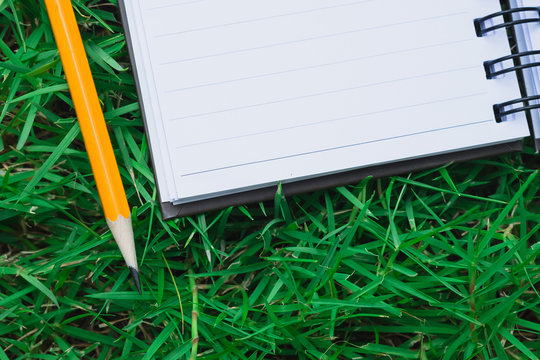 To do list in notebook - reminder notebook with pencil on space green field grass in flat lay, to do reminder write down on notebook with pencil, simple task list reminder on nature green field