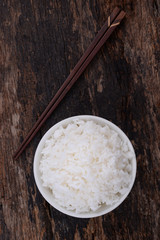 Cooked rice in bowl on wood background.