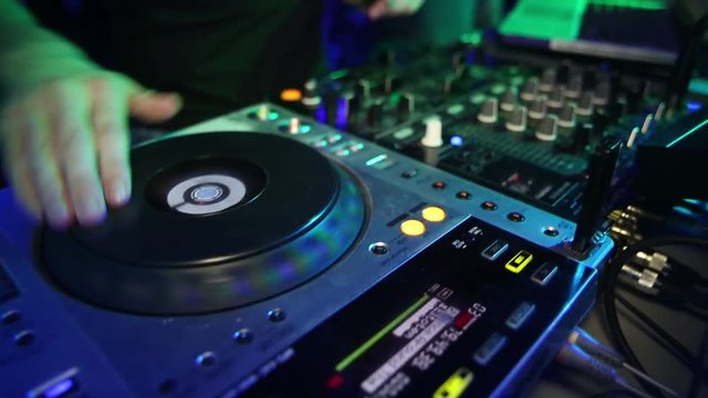Hands of DJ which mixes music tracks with CD-players and mixer in nightclub