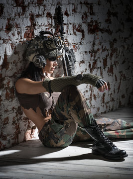 Woman soldier with a gun sitting on the floor