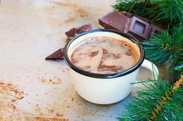 Enamel mug of hot chocolate cocoa  and slice of bitter chocolate on metal vintage background with fir tree. Winter times drink concept. Delicious cold weather beverage.Copy space.