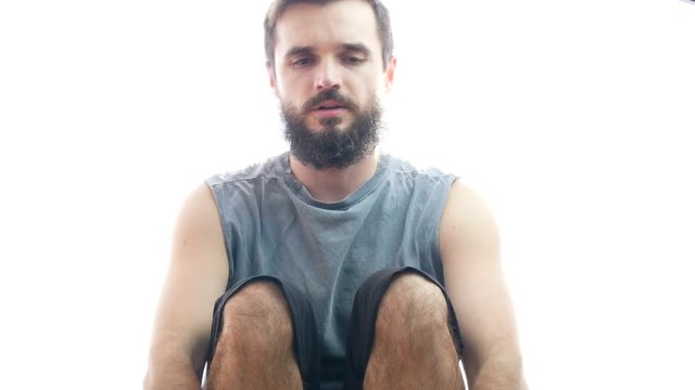 Young bearded man working out on the rowing machine, studio isolated on white background.