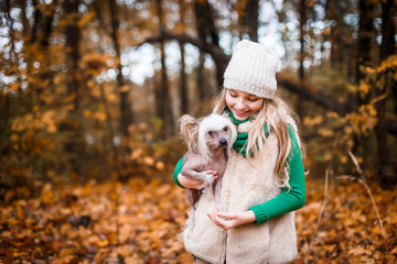 Fototapeta premium A pretty girl with a chinese crested dog outdoors in autumn