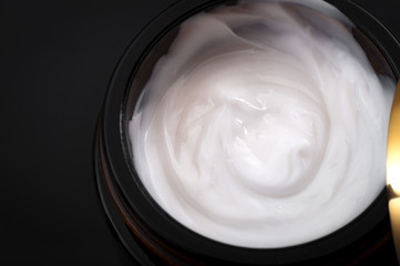 Beauty and cosmetics concept with closeup on a moisturizing cream in an open jar with copy space on a dark background, Close-up and macro photography
