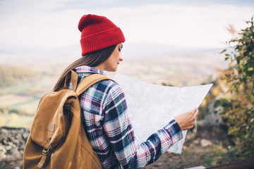 Hipster girl with red wool cap checking map