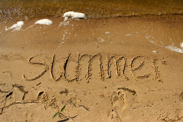 Inscription summer on the sand by the sea with waves