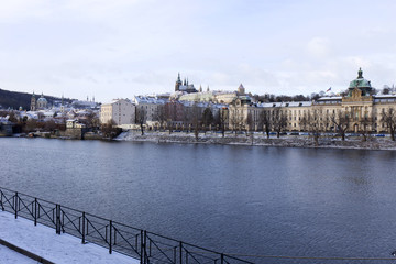 Obraz premium Snowy freeze Prague Lesser Town with gothic Castle above River Vltava, Czech republic
