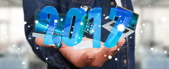 Businessman holding 2017 3D rendering text with tech devices