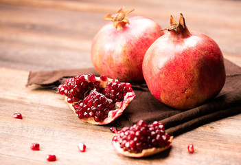 Pomegranate fruits with grains on wooden table.