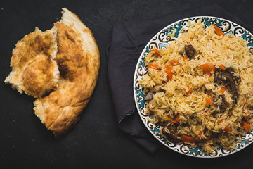 Pilaf on plate with oriental ornament and Traditional Asian breads - churek. Plov. Top view.