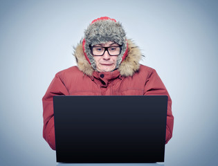 Funny man in winter clothing in front of a laptop. Russian hacker concept