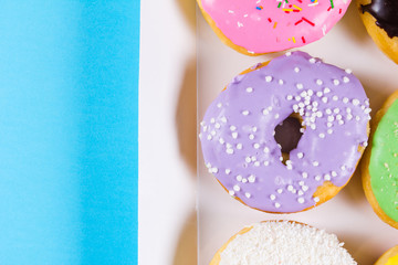 Six colorful round donuts in the box. Flat lay, top view.