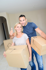 happy young couple carrying cardboard boxes moving into their new house