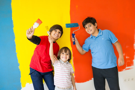 Adorable boy in bright paint with mess of paint child on wall