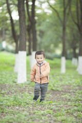 Happy Chinese baby boy running in woods