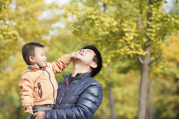 Happy real father and son playing in front of ginkgo trees