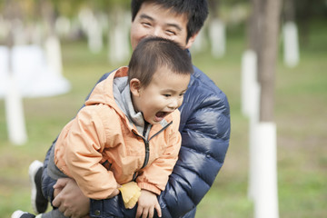 Fototapeta premium Happy real father and son playing in front of ginkgo trees