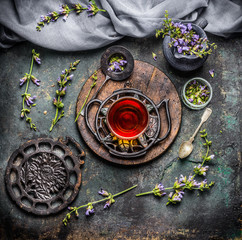 Soothing cup of herbal tea with freshest organic ingredients: herbs and flowers on rustic vintage background with tea tools, top view