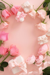 Frame of beautiful pink tone roses and gift boxes on pastel pink background,top view