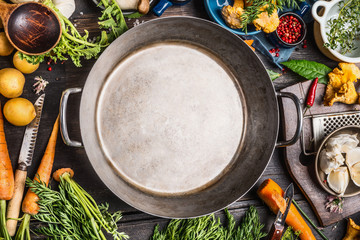 Healthy or diet food background with empty cooking pot and various vegetables and seasoning ingredients, top view, frame