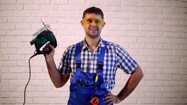 Man with an electric jig saw.  Working with electric jig saw. Construction worker with a power tool.