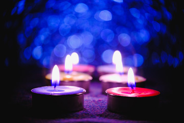 Candle flame light at night with abstract circular bokeh background Christmas lights.