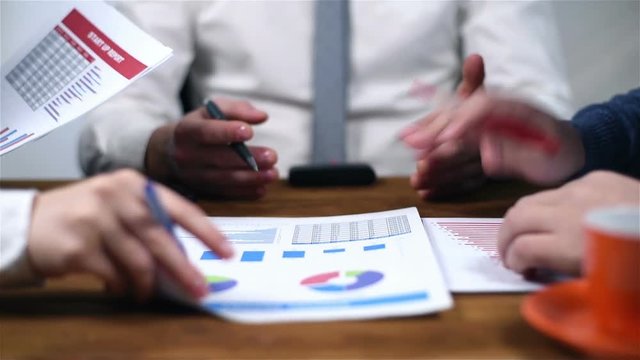 Three Businesspeople Sitting In Office And Checking Financial Report