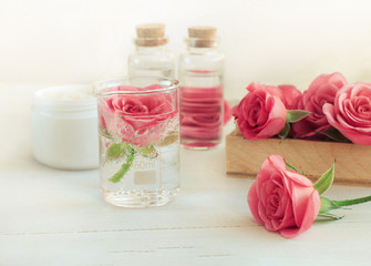 Obraz na płótnie Canvas Rose scent holistic cosmetic. Fresh pink blossom, array of glass vials and apothecary bottles. Flower Aromatherapy. Soft light and focus. 