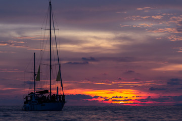 Silhouette of a sailboat against colorful vivid sunset sky