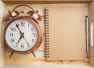 vintage alarm clock, pen and notepad in wooden crate