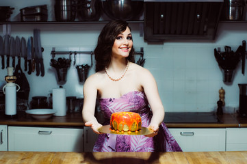 Smiling hostess holds cake like big donut with red fondant