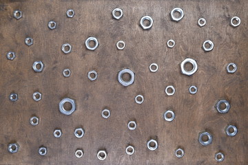 Steel nuts on wooden background top view