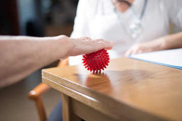 ältere Frau trainiert mit einem Igelball auf dem Tisch