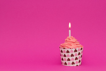 cupcake with white candle on pink background