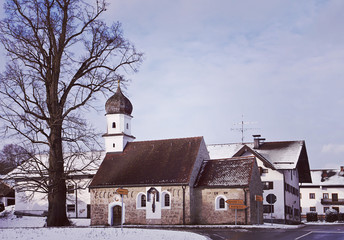 Fototapeta na wymiar Bavarian winter landscape with snow, crossroad and ancient chapel with onion dome