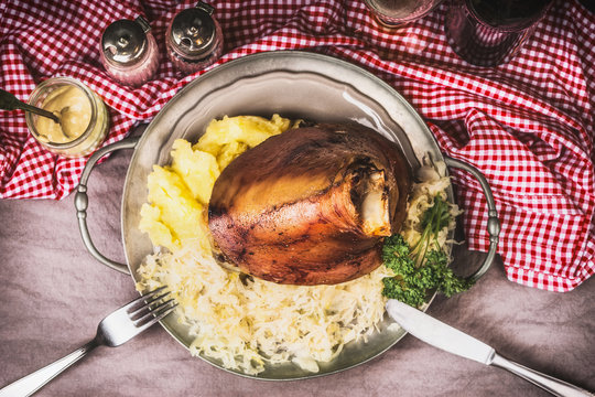 Roasted eisbein with Mashed Potatoes and pickled cabbage served on plate with cutlery , top view